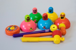 The five brightly coloured "whack attack" domes show all the heads of the characters.  There is a plastic timer and three brightly coloured plastic hammers in the foreground.